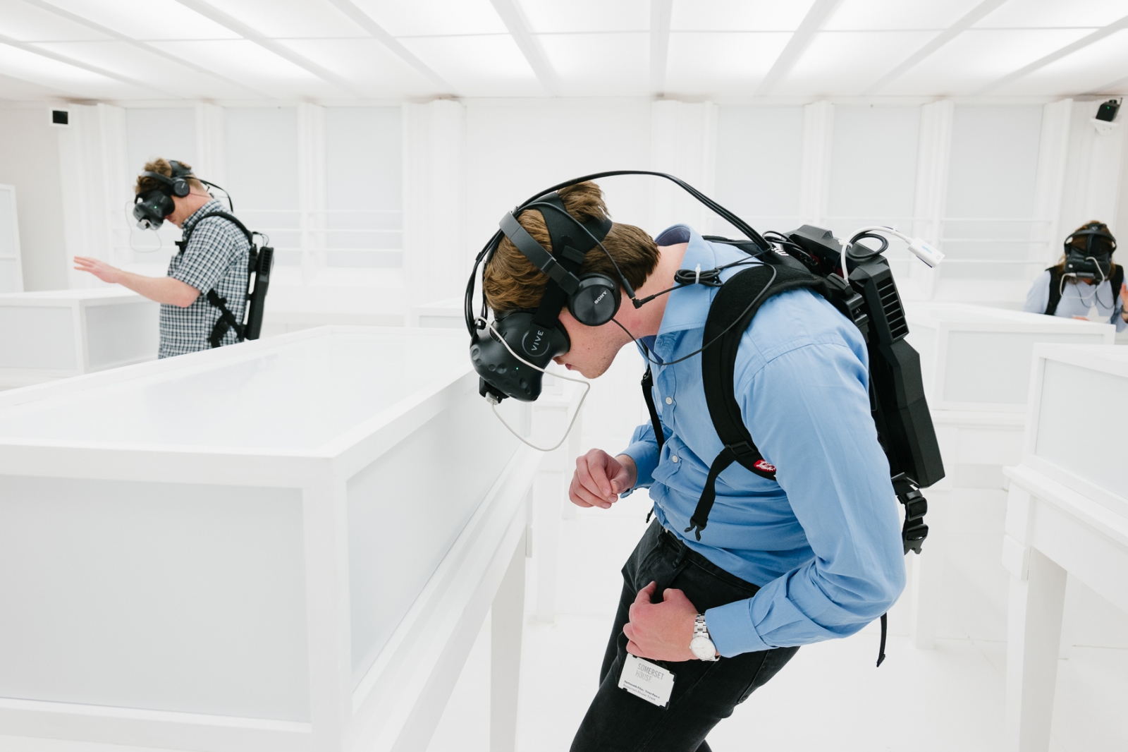 Ausstellungsbesucher mit VR-Brillen vor augenscheinlich leeren Wänden und Vitrinen