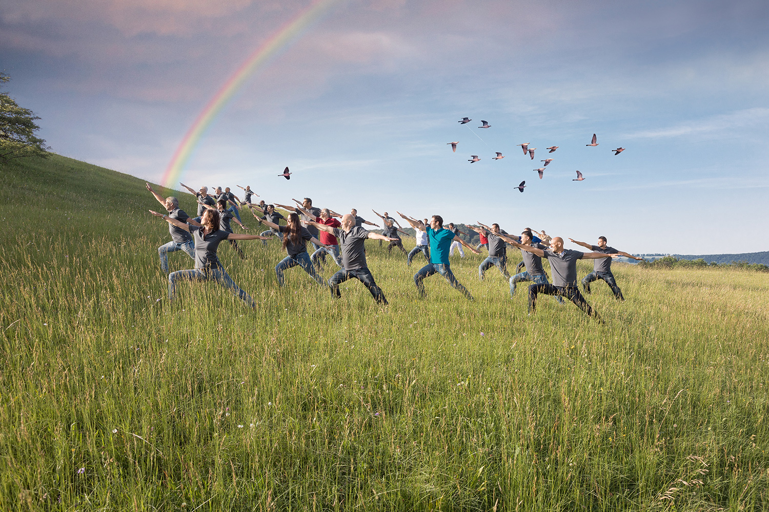 MBA Team in meditativer Pose in der Natur mit Regenbogen